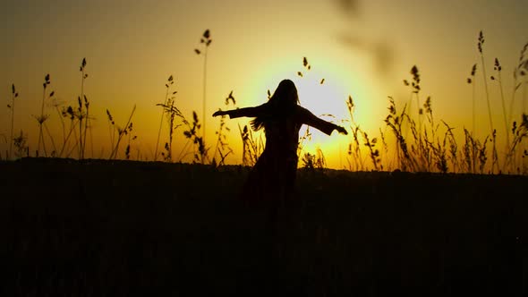 Carefree Woman Whirling on Meadow in Evening Glow