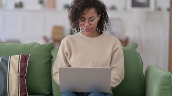 Successful African Woman with Laptop Celebrating on Sofa