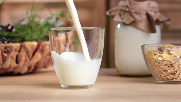 Pouring Farm Organic Milk From Jug to Glass Cooking Homemade Village Breakfast on Wooden Table