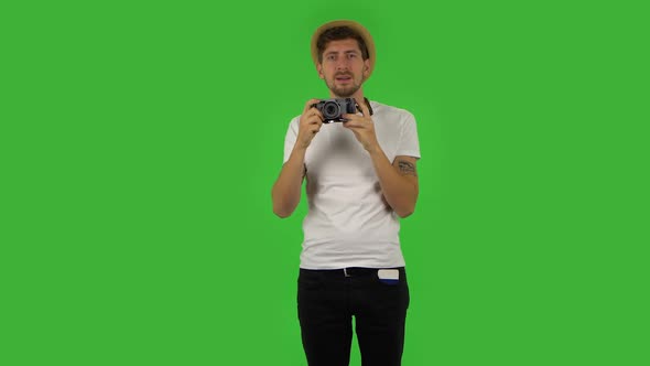 Tourist in Hat on Vacation Takes Pictures on a Retro Camera. Green Screen
