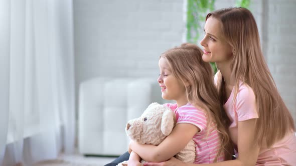 Happy Mother and Daughter Having Friendly Conversation Hug Toy Bear