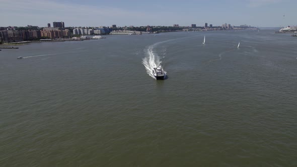 Aerial view over a ferry on Hudson river, in sunny New York, USA - tilt, drone shot