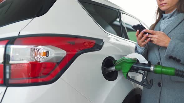Woman Using Smartphone While Her Car is Refueling