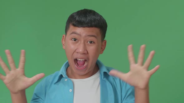 The Shocked Young Asian Boy Grabbing Her Head While Saying Wow On Green Screen Background