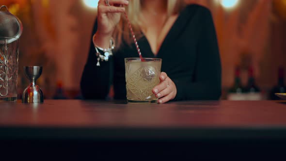 Anonymous woman mixing and serving cocktail during work in stylish bar