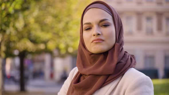 A Young Beautiful Muslim Woman Shows a Thumb Down to the Camera and Shakes Her Head in a Street