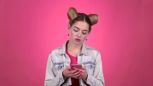 Girl Is Testing a Phone and Showing a Thumbs Up. Pink Background. Slow Motion