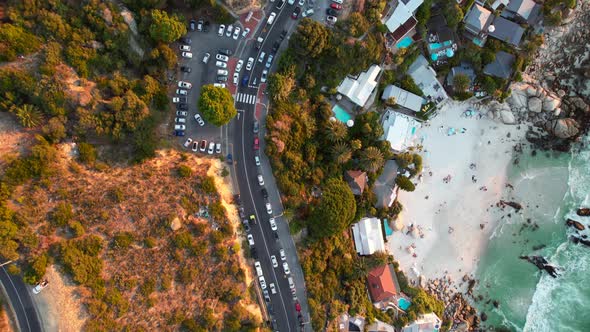 top down of Clifton beach road with traffic driving at sunset in Cape Town, aerial