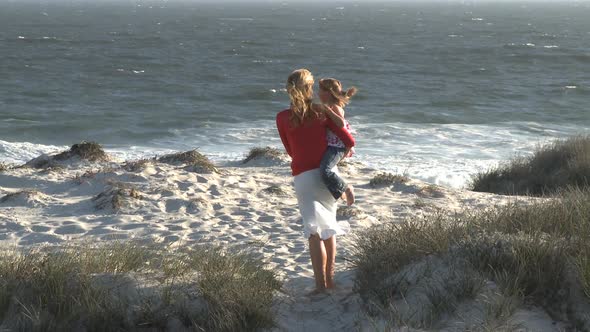 LS OF A MOTHER AND DAUGHTER STANDING ON A BEACH