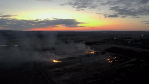 Aerial view of a Grass fire at Dusk. Fly over Wild fire. Flying above burn field at Sunset.