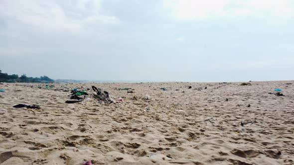 Low aerial flying over beach sand with garbage, Vietnam