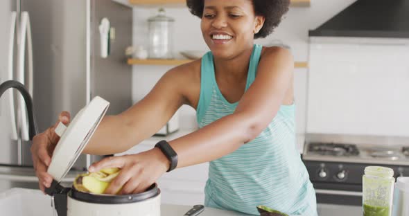 Happy african american woman cleaning, throwing away waste in kitchen