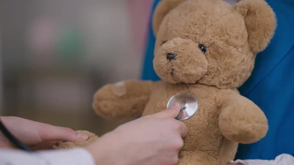 Closeup Brown Teddy Bear with Child Hand Using Stethoscope Auscultating Toy