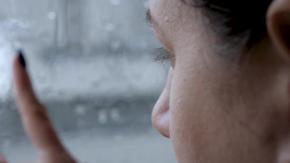 Sad Woman Looks At Street In Rain Through Window And Puts Her Hand On Glass