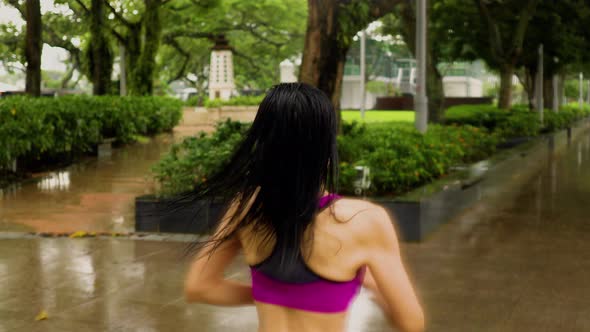 Middle-aged Asian woman jogging in the rain in Singapore 