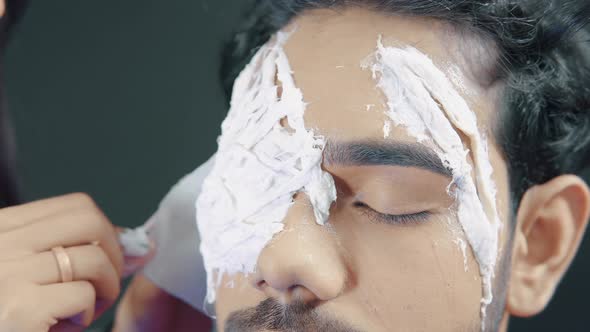 Make up artist applying white prosthetic insert on man's face to make a Halloween mask