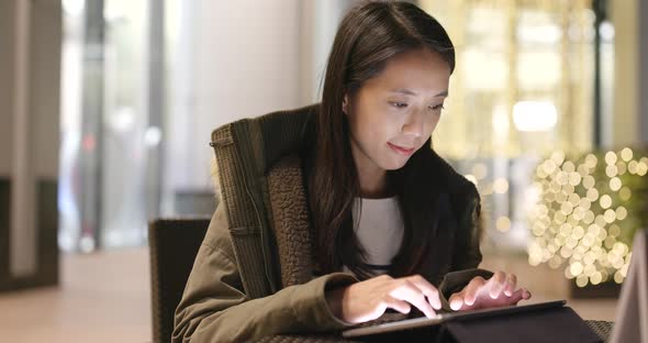 Woman look at tablet computer in coffee shop at night