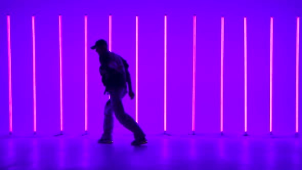 Cool Young Guy Breakdancer Dancing Hip Hop in Colorful Background with Neon Lamps