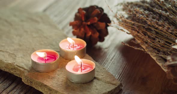 Blowing out Three Orange Tealight Candles and Swirling Fumes on Wooden Table in Cozy Environment