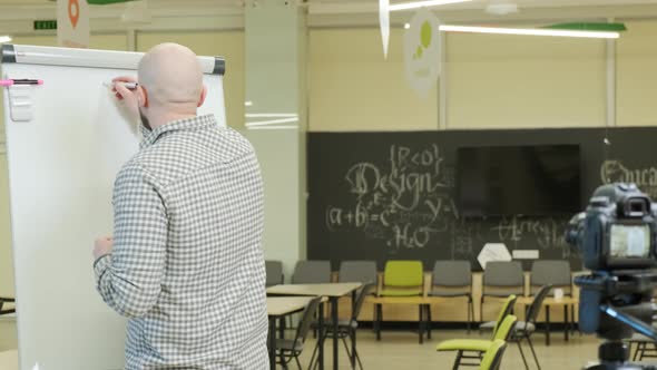 Teacher Records Mathematics Lessons He Stands and Writes with a Pen on a Flip Chart