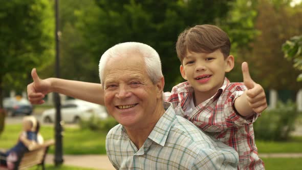 Little Boy Shows His Thumbs Up on His Grandpa's Back