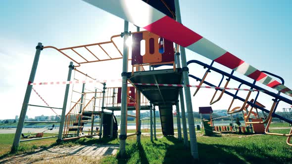 Empty Playground During Coronavirus Pandemic. Barricade Tape on a Sunlit Playground with Nobody in