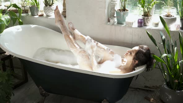 Woman washing legs in the bathtub.