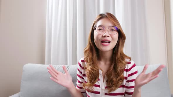 Asian young woman with prescription glasses looking at the camera and smiling.