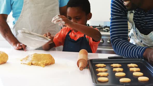 Boy preparing cookies with his father and grandfather