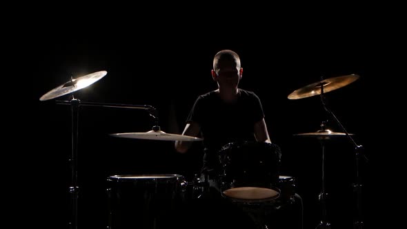 Musician Plays Professionally Good Music on Drums Using Sticks. Black Background. Silhouette