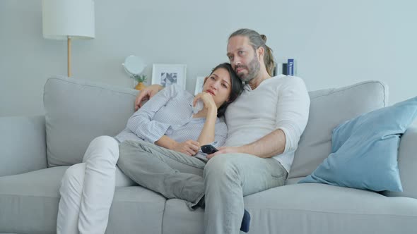 Caucasian loving couple watch movie together in living room at home.