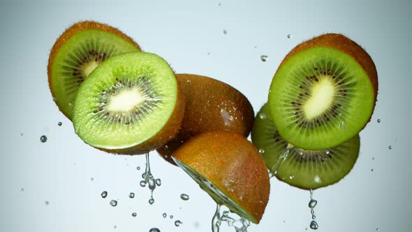 Super Slow Motion Shot of Flying Kiwi Slices and Splashing Water on Ligh Blue Background at 1000Fps