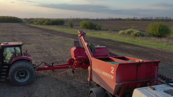 Aerial View of a Truck Loading a Trailer with Seeds for Planting Man on Trailer