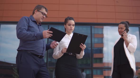 A Business Woman is Looking at Working Papers While a Businessman and a Business Woman are Taking