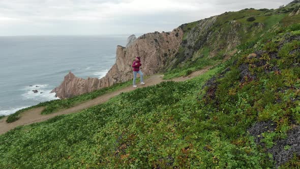 Girl Walks Up on Rocky Mountain Against Hills and Ocean