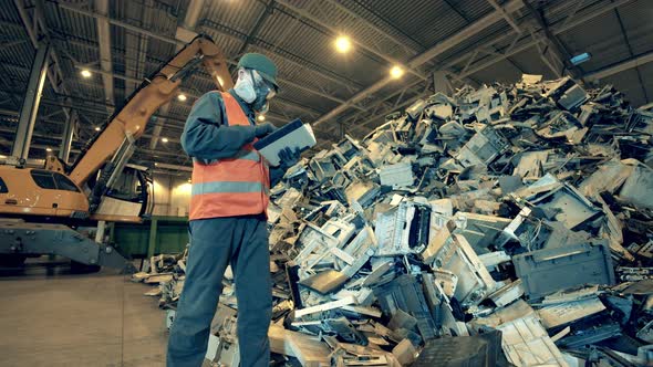 Dumpsite Inspector with a Tablet Observing a Pile of Waste