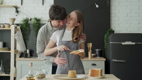 Young Couple Applying Peanut Butter on Bread in the Morning