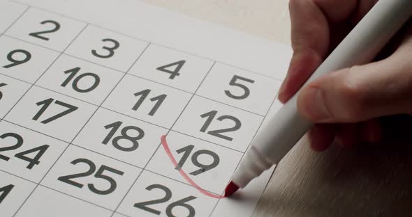 Man's Hand Write Down the 19Th Day on the Paper Calendar Using a Red Pen