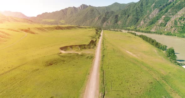 Aerial Rural Mountain Road and Meadow at Sunny Summer Morning. Asphalt Highway and River