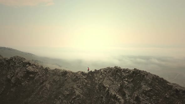 Aerial Close Up  Female Hiker Proudly Standing on Mountain Top on a Cold Cloudy Day in Autumn