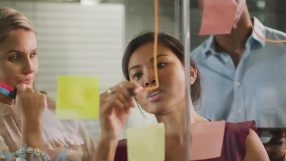 Professional businesspeople discussing while writing on the whiteboard in modern office in slow moti