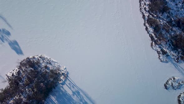 Aerial birdseye view of snowy bog landscape with frozen lakes in sunny winter day, Dunika peat bog (