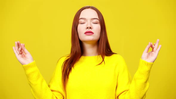 Middle Shot of Slim Cute Redhead Woman Meditating at Yellow Background