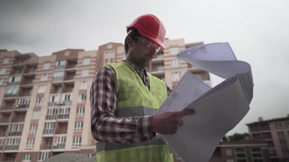 Builder Reading Blueprints on Construction Site