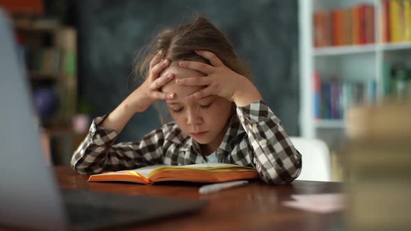 Closeup of Exhausted Upset Primary Child School Girl Banging Head Against Table Writing Difficult