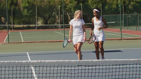 Video of happy diverse female tennis players holding rackets and talking