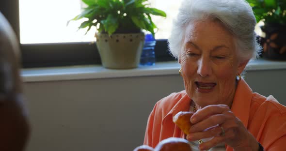 Senior woman taking cupcake from tray 4k