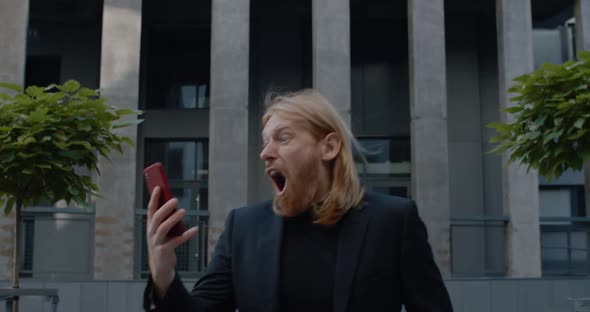 Close Up of Happy Businessman Looking Excited and Celebrating Success While Touching Phone Screen