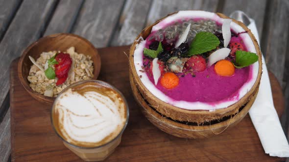 Top View of Tropical Breakfast Consisted of Smoothie Served in Coconut Shell with Muesli on a Side