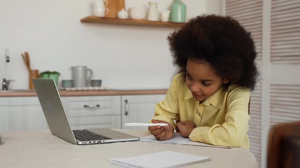 Little African American Girl Uses Laptop to Video Call with Teacher